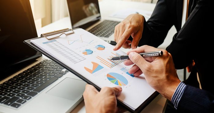 Business concept. Business people discussing the charts and graphs showing the results of their successful teamwork. Selective focus.